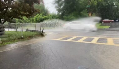 car drives through puddle on street in troy new york during heavy rain
