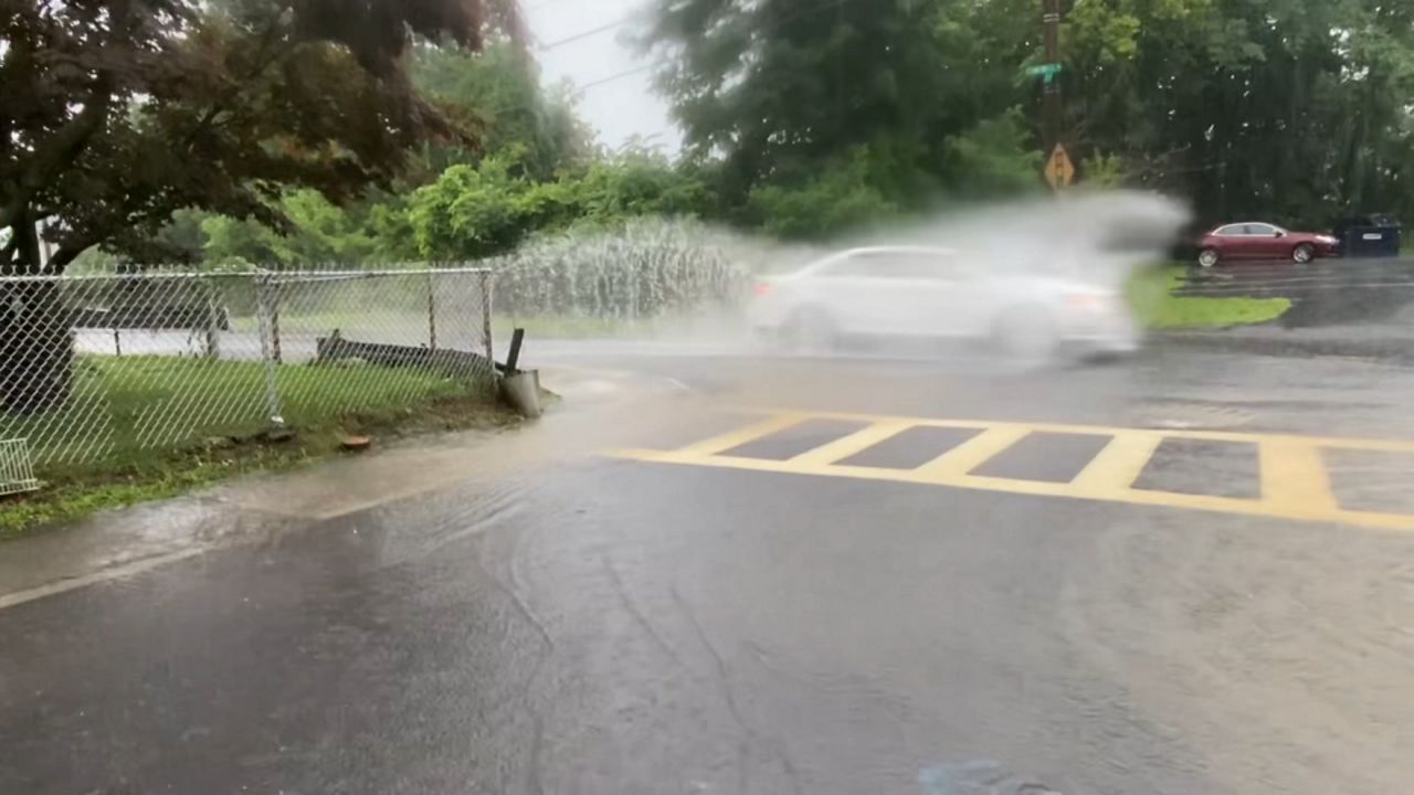car drives through puddle on street in troy new york during heavy rain