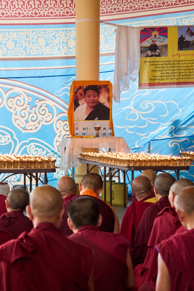 Lamps are lit in front of a photograph of Lobga Rangzen (Lobsang Palden), who died after setting himself on fire in front of the United Nations headquarters in New York on Thursday, at a special prayer ceremony by exiled Tibetans at the Tsuglakhang temple in Dharamshala, India, Saturday, July 4, 2026. (AP Photo/Ashwini Bhatia)