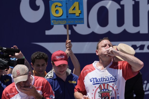 Joey Chestnut and other competitive eaters consume hot dogs during the 2026 Nathan's Famous Fourth of July hot dog eating contest at Coney Island in Brooklyn on Saturday, July 4, 2026. (AP Photo/Anna Connors)