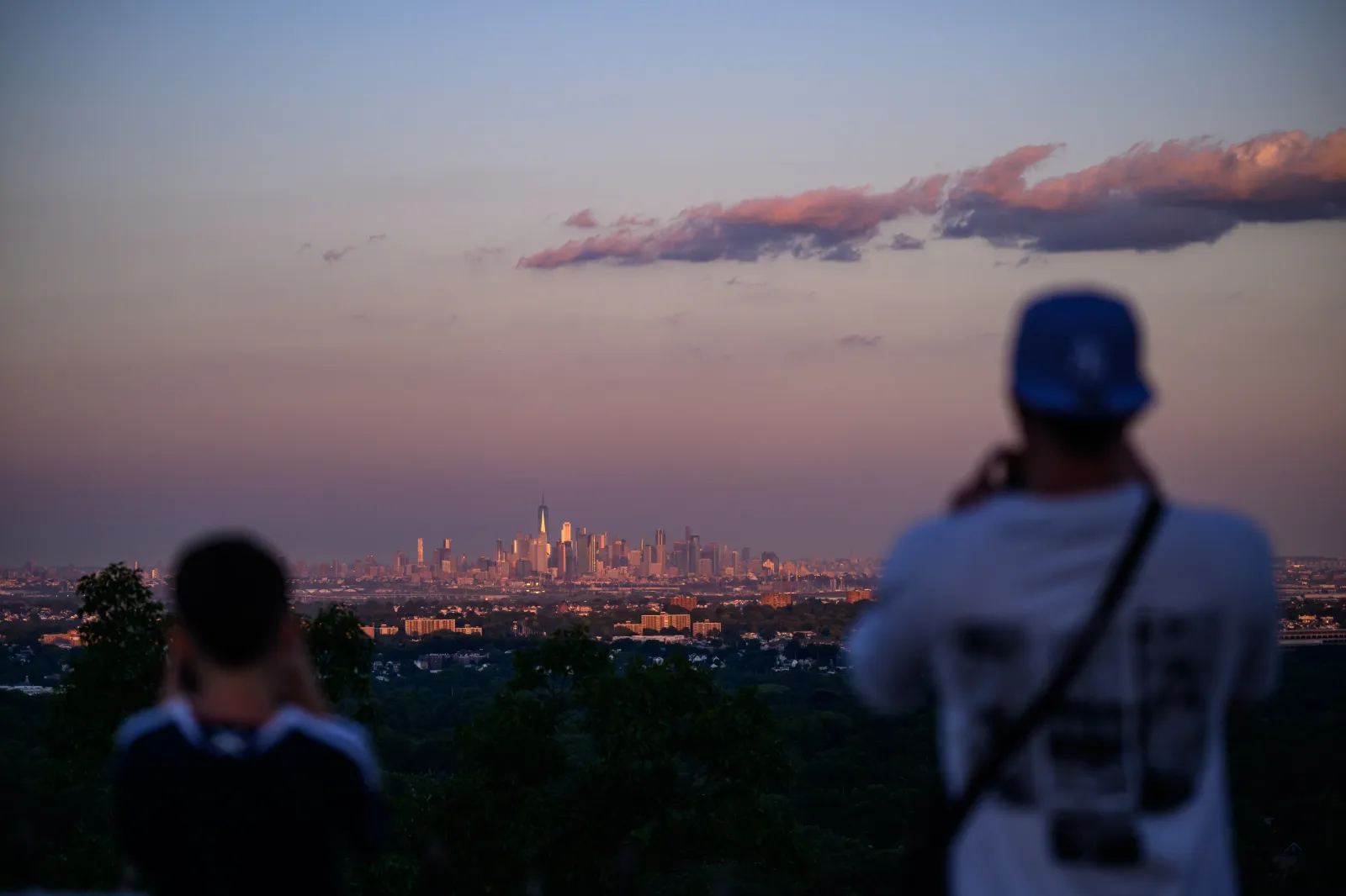 People take pictures of the Manhattan and New Jersey skylines at sunset.