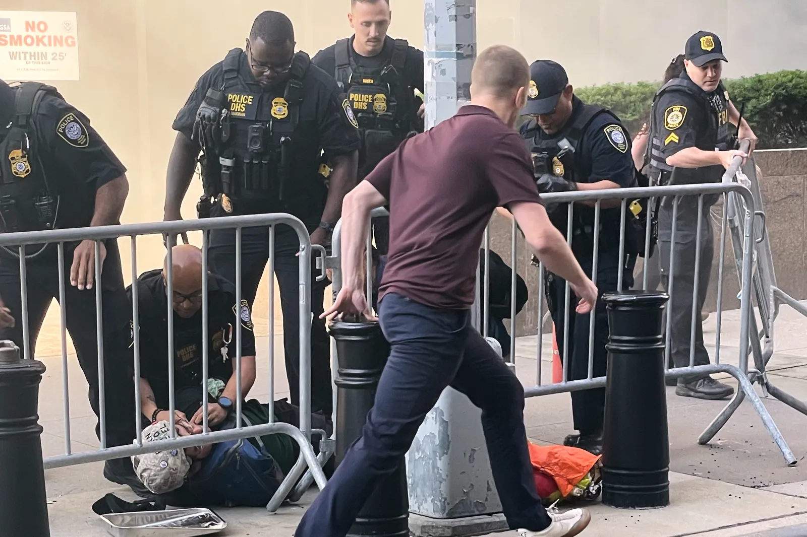 Several officers surround a person on the ground near the site of a fire at 26 Federal Plaza in lower Manhattan on July 20, 2026.