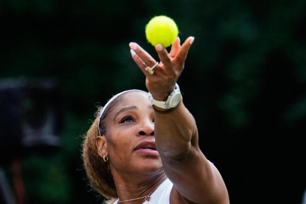 Serena Williams tosses a ball to serve.