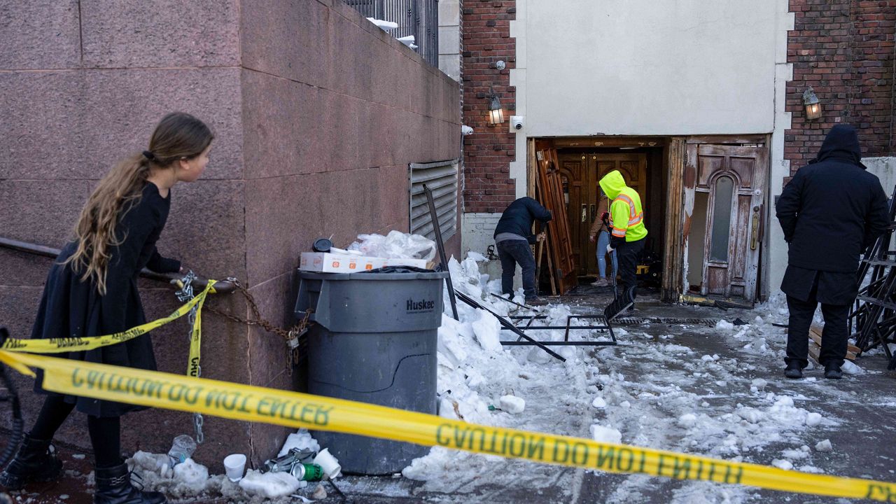 People clean up after a car slammed into the entrance of the Chabad Lubavitch world headquarters, Jan. 29, 2026, in New York. (AP Photo/Yuki Iwamura, File)