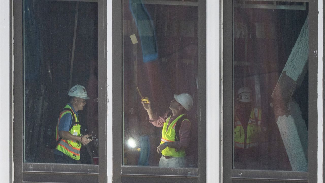People inspect a buckled support beam inside 235 East 42nd Street, Wednesday, July 8, 2026, in New York.