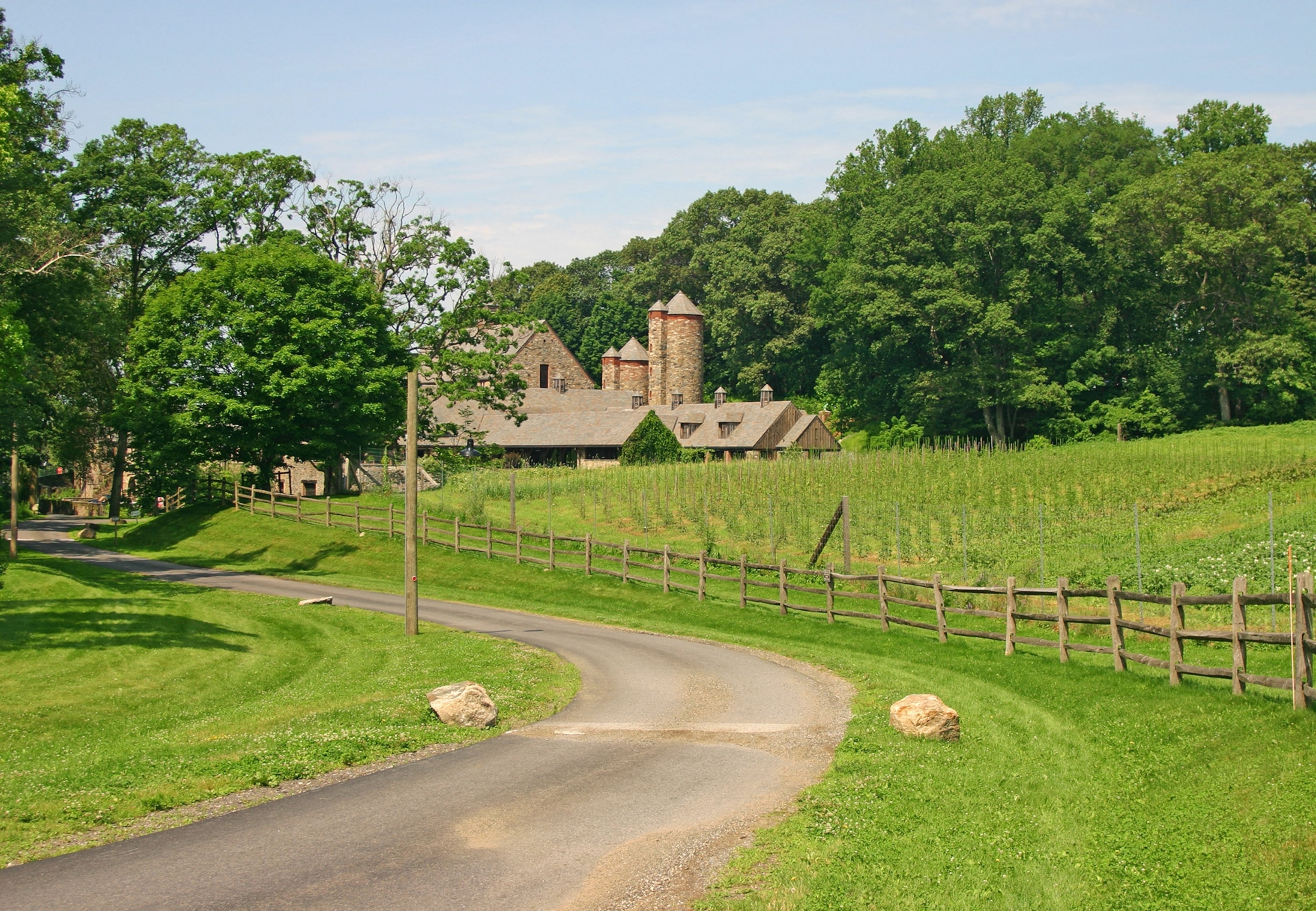 A winding path leads toward a farm house surrounded by green lawn and trees