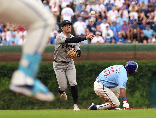 Cubs first baseman Michael Busch, left, grounds into a double play as Yankees shortstop Anthony Volpe touches second and throws to first during the first inning Friday, July 31, 2026, at Wrigley Field. (Stacey Wescott/Chicago Tribune)