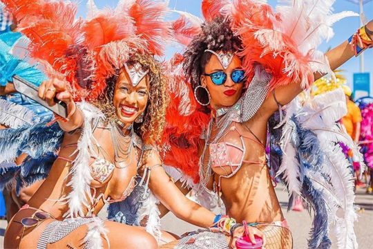 Two Carnival revelers, ladies dressed in colorful feathers.