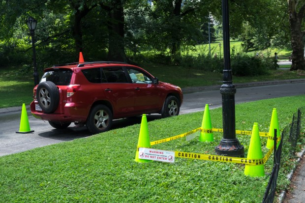 A ConEd site-safety monitor sits in a car beside a lamp post guarded with yellow tape at Cherry Hill. (Evan Simko-Bednarski/New York Daily News)