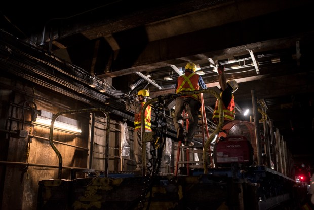 MTA contractors wrap wires along the ceiling of the tunnel beneath Queens. (Evan Simko-Bednarski / New York Daily News)