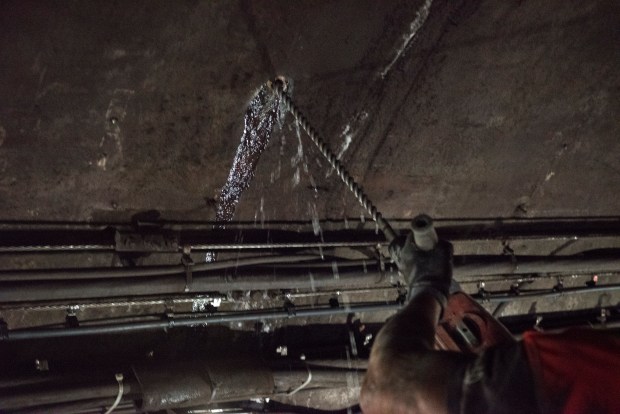 Water sprays from a hole after an MTA contractor drilled through the tunnel's concrete liner.Work crews wrap wires south of Court Square subway station in Long Island City, Queens. (Evan Simko-Bednarski / New York Daily News)