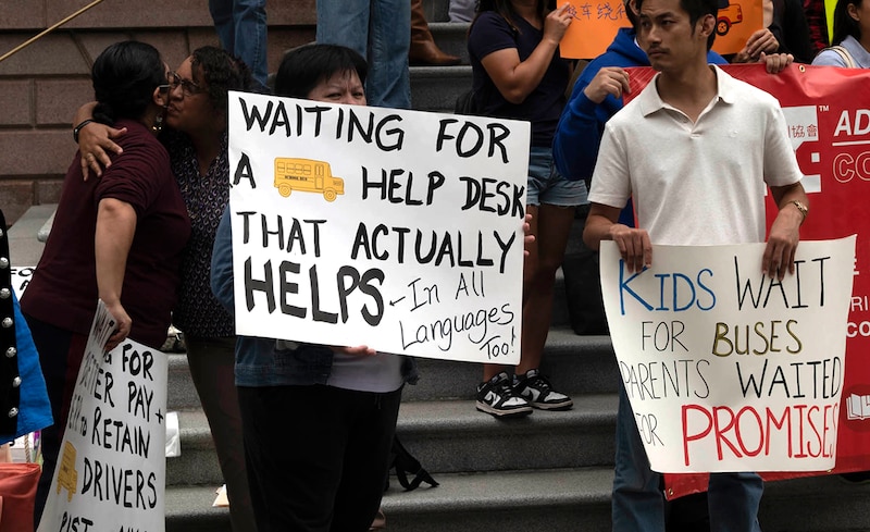 A group of people stand on steps holding signs.