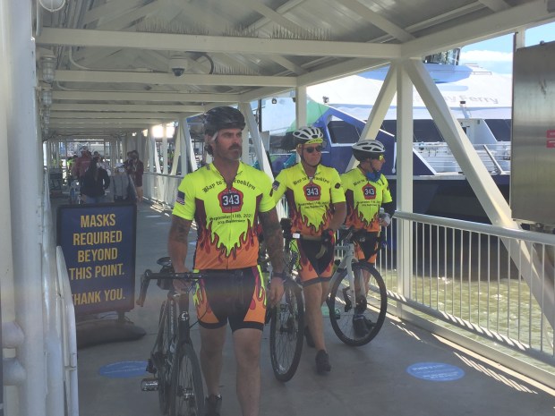 Cyclists of bay2brooklyn come off the Vallejo ferry to hear applause from people at the waterfront and Mare Island Brewing nearby. The cyclists will begin a 36-day trip to Brooklyn to honor those that fell on 9/11. (Thomas Gase - Times-Herald.)