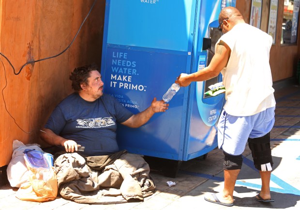 A Torrance resident gives Andrew Truelove a bottle of water and some snacks at a gas station in Torrance, California, on July 18, 2023, during a feature story profile on homelessness by the Los Angeles Times. (Genaro Molina/Los Angeles Times via Getty Images)