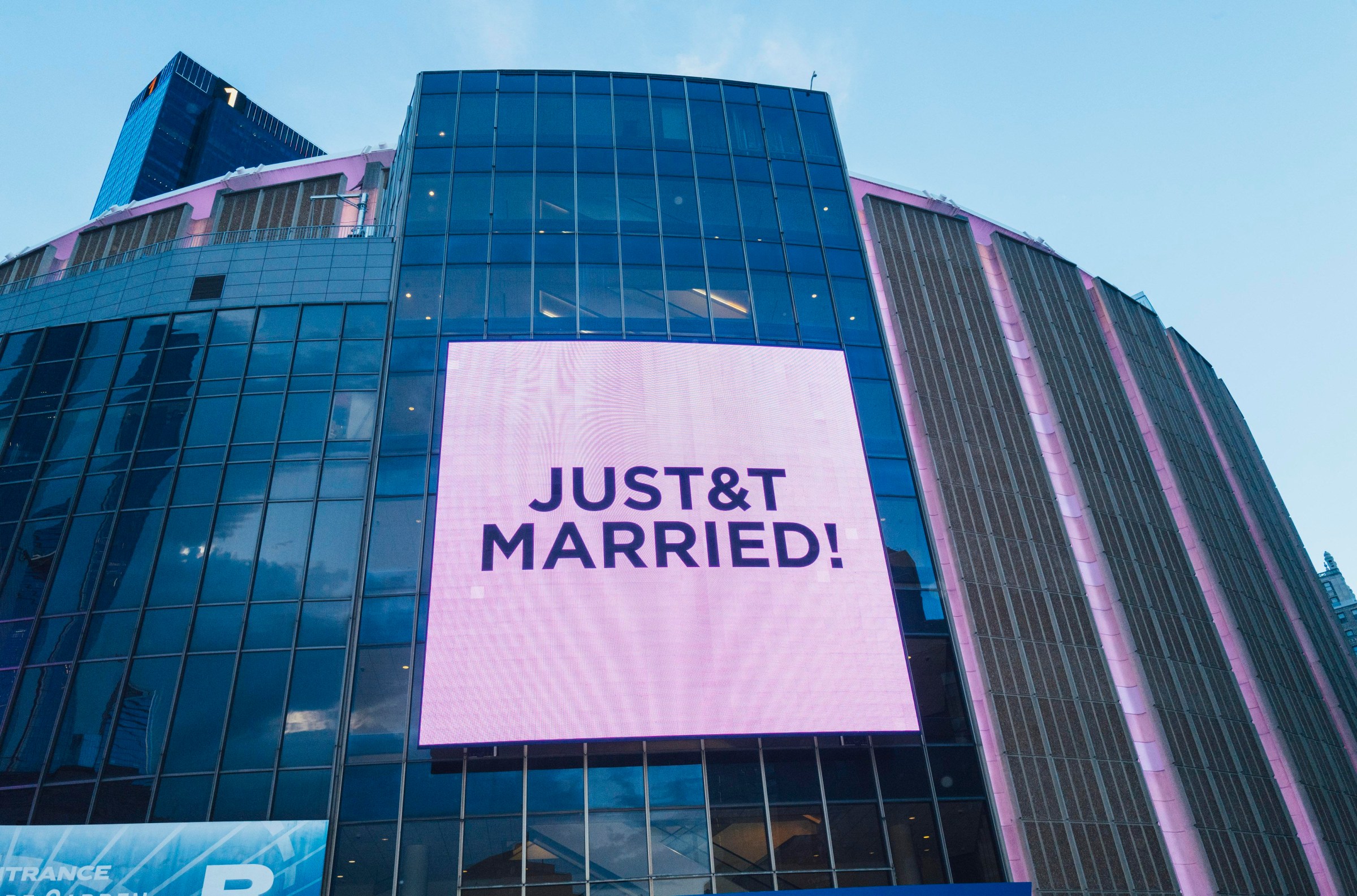 The outside of an arena with a purple electric sign reading “JUST&T MARRIED!”