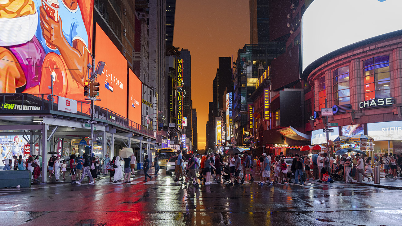 People cross 7th Avenue during a colorful sunset in Times Square after a rain shower on July 03, 2026 in New York, New York. The heat wave, stretching from the midwest to east coast, will affect as many as 90 million Americans.