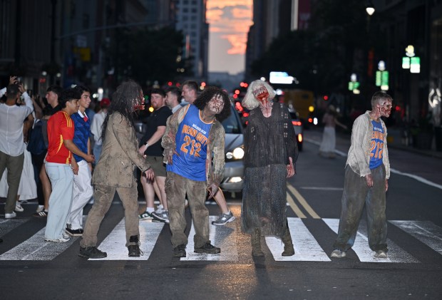 NEW YORK, NEW YORK - JULY 11: Walkers participate in Dead City NYC Activation with Manhattanhenge on the background on July 11, 2026 in New York City. (Photo by Roy Rochlin/Getty Images for AMC Global Media )