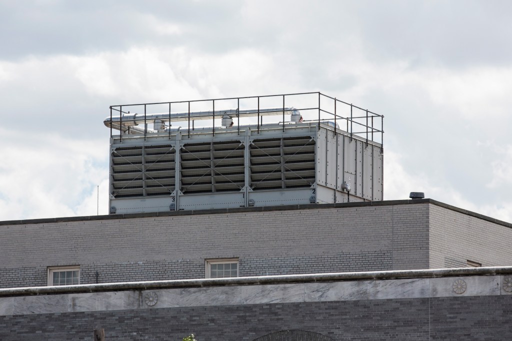 Cooling tower on the roof of a brick building.