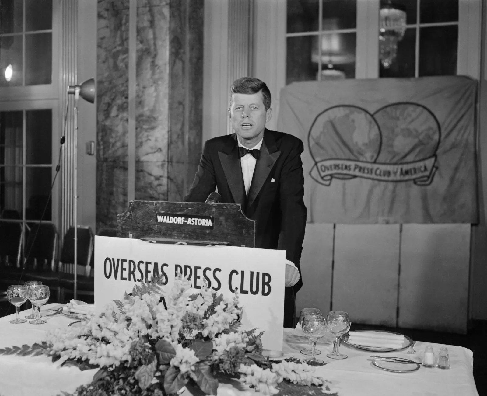 John F. Kennedy is shown addressing the annual awards dinner of the Overseas Press Club of America at the Waldorf-Astoria Hotel in New York City in the 1950s.