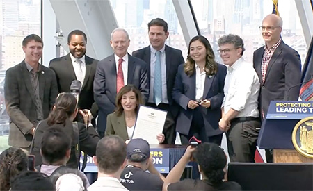 Hochul EO Signing New York Gov. Kathy Hochul signs Executive Order No. 62 surrounded by lawmakers and supporters at a signing ceremony.