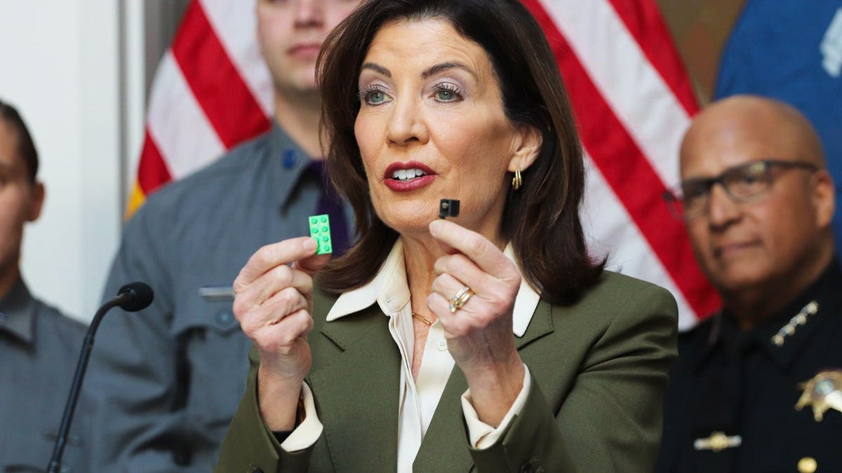 Gov. Hochul holds up a 3D-printed gun part, alongside a Lego piece for size comparison, during a press conference held at the New York State Police Forensic Investigation Center in Albany on March 23, 2026.