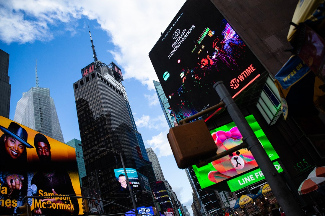 Looking up at Times Square billboards and skyscrapers in New York City.