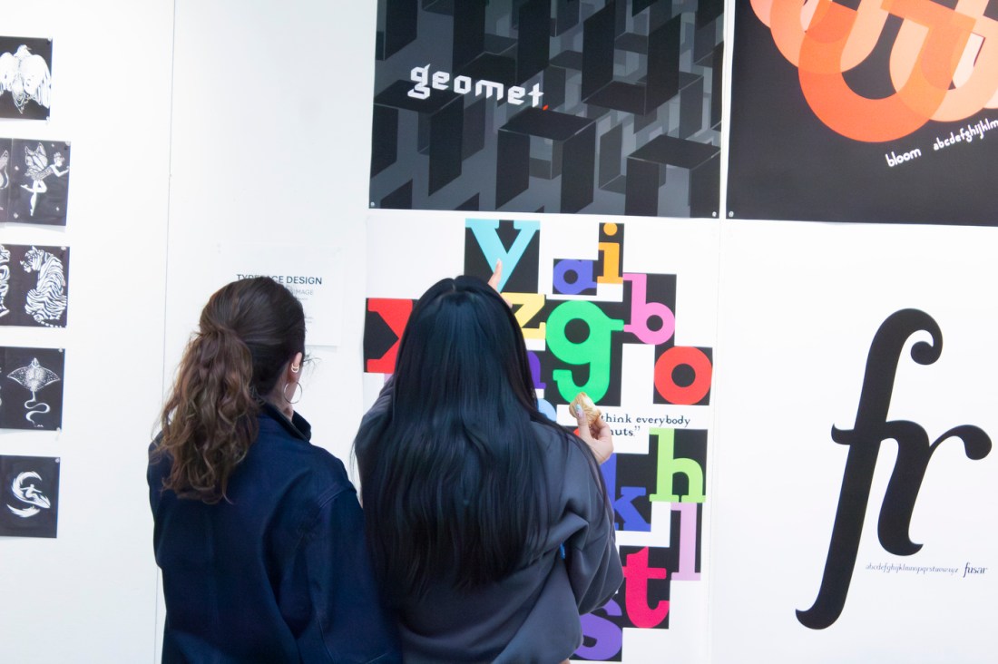 Two students look at a colorful display of different type face designs.