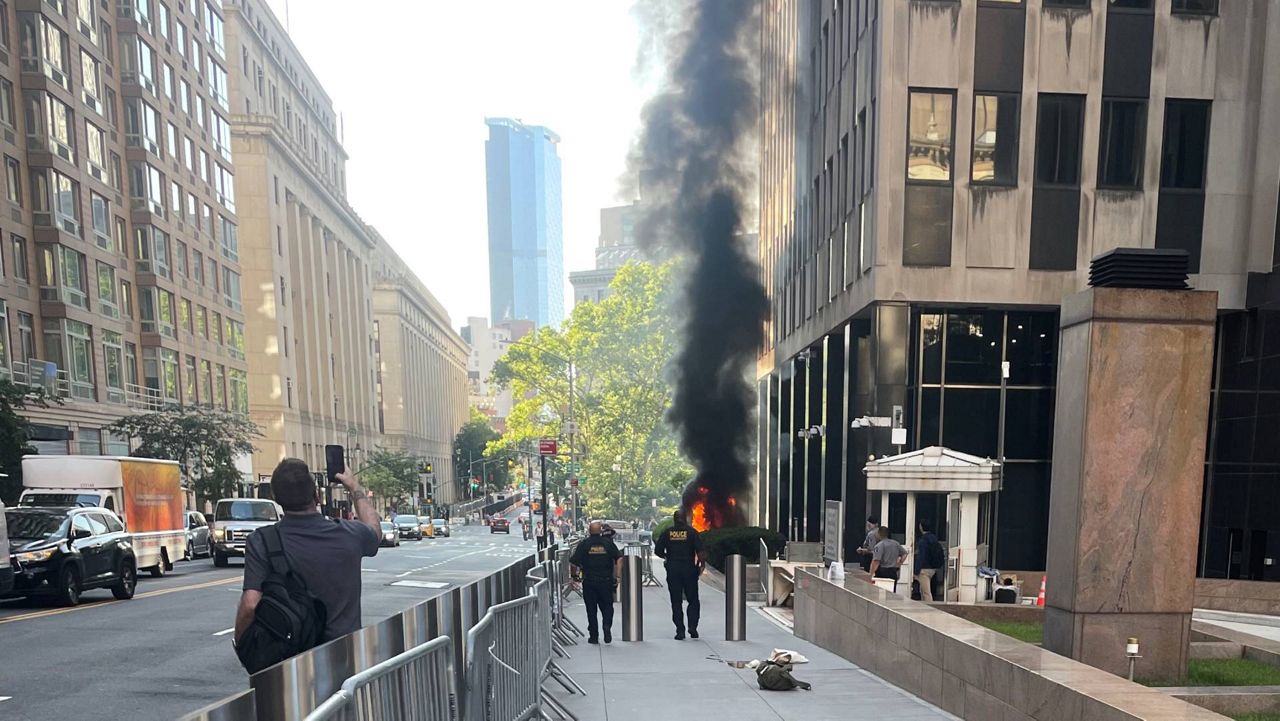 This photo provided by Robert Sullivan shows black smoke and flames in front of 26 Federal Plaza in lower Manhattan, Monday, July 20, 2026, in New York. (Robert Sullivan via AP)
