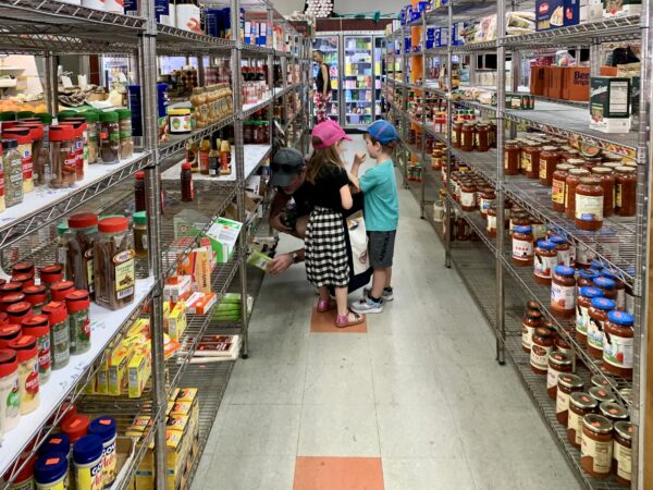Kids join their dad in picking up some essentials on the last day of operation for All in One Deli Mart, also known as Peas N’ Pickles. Photo: Mary Frost/Brooklyn Eagle