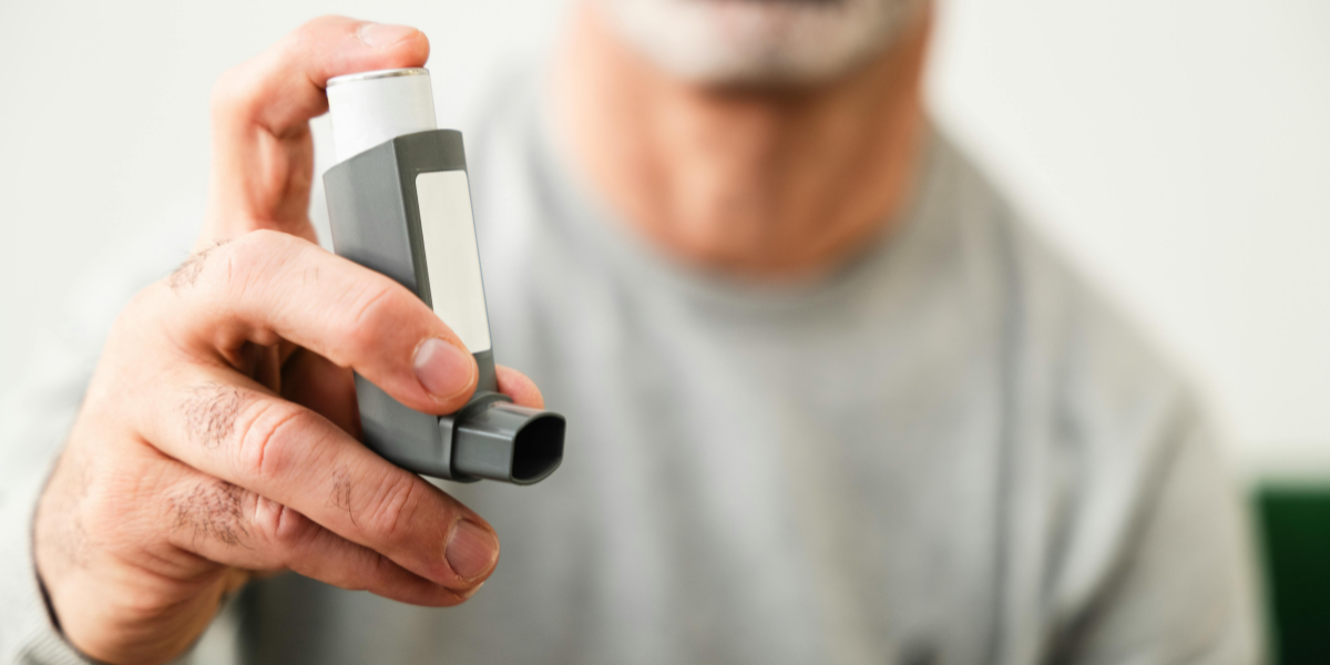 close up of a man's hand holding an inhaler used for asthma medication