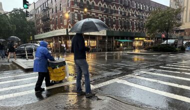 A person with an umbrella waits to cross a street in New York City. (Spectrum News NY1/Christina Santucci)