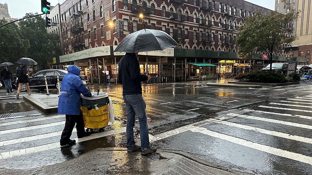 A person with an umbrella waits to cross a street in New York City. (Spectrum News NY1/Christina Santucci)
