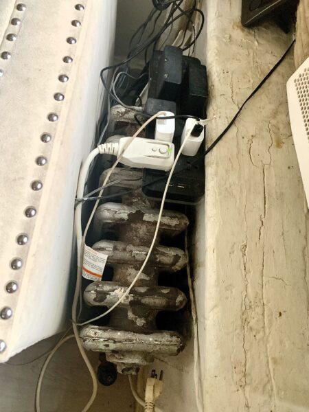 A full power strip sits on top of a radiator that emits hot steam in the winter. Photo: Mary Frost/Brooklyn Eagle