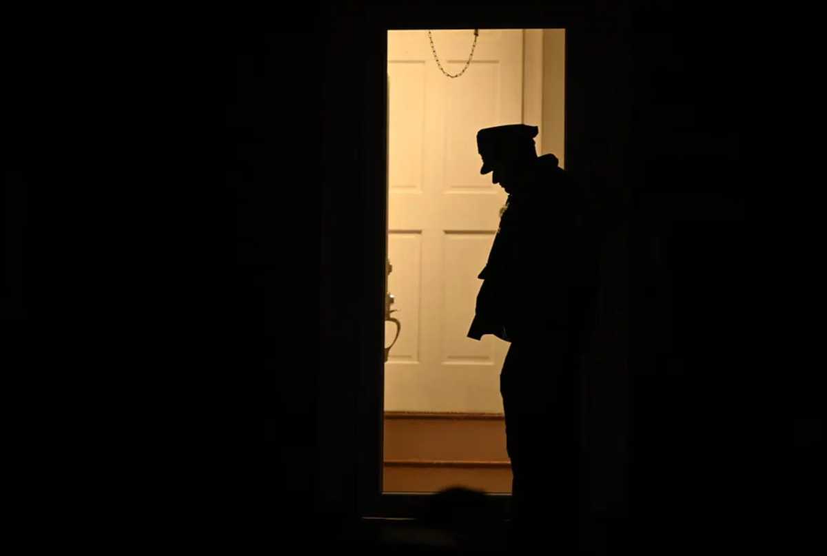 Silhouette of police officer standing in doorway of Brooklyn crime scene