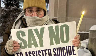 A demonstrator against assisted suicide displays a sign during a candlelight vigil outside the Sen. John H. Hughes Office Building in downtown Syracuse on Dec. 4, 2025. New York's new medical assistance in dying law goes into effect on Aug. 5, 2026.