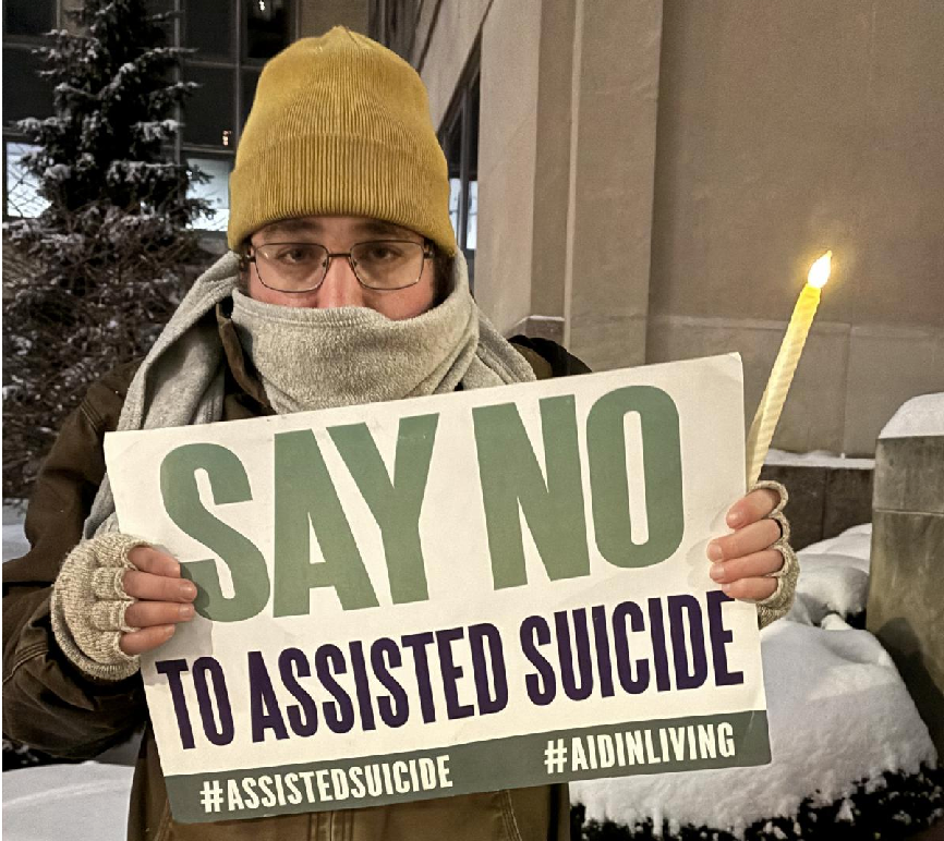 A demonstrator against assisted suicide displays a sign during a candlelight vigil outside the Sen. John H. Hughes Office Building in downtown Syracuse on Dec. 4, 2025. New York's new medical assistance in dying law goes into effect on Aug. 5, 2026.