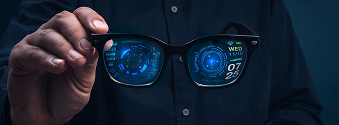 A person holds smart glasses displaying digital interfaces and data, including a clock, date, and various futuristic graphics, projected on the lenses against a dark background.