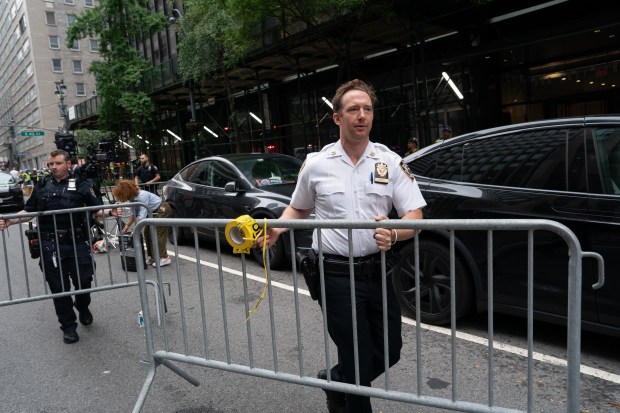 A NYPD captain moves barricades closing off another block of Second Ave. due to a partial building collapse.