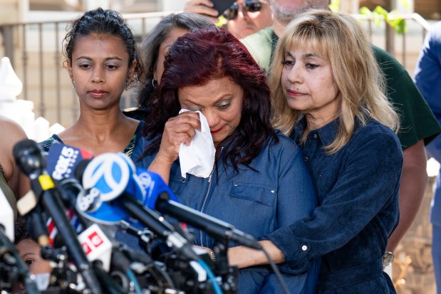 Carol Acevedo, mother of Sgt. Angel Sarah Rampersad, wipes away a tear next to Rampersad's sister, Laura Tamby (left), and aunt, Judy Rackal (right), during a press conference in front of Rampersad's home on 96th St. in Ozone Park, Queens on Thursday, July 23, 2026. (Theodore Parisienne / New York Daily News)