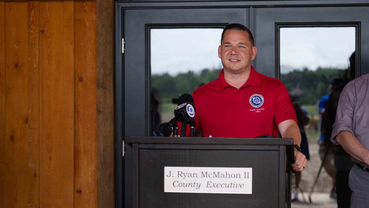 ryan mcmahon stands at podium with his name and title on the front of it