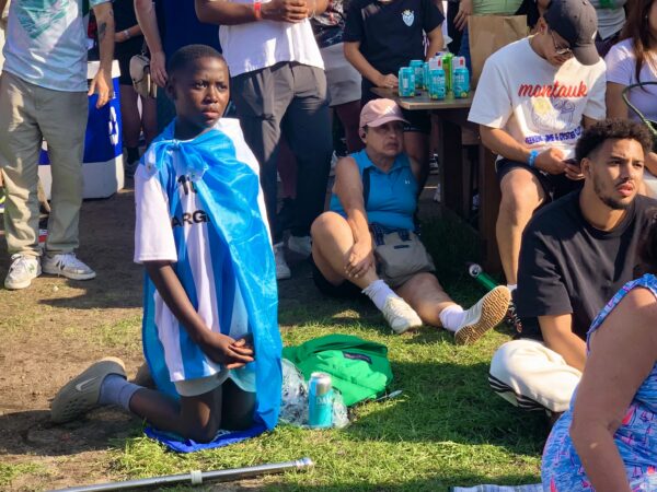 A boy draped in a flag watches the final World Cup match at the adidas Fan Zone in Brooklyn Bridge Park. Photo: Mary Frost/Brooklyn Eagle
