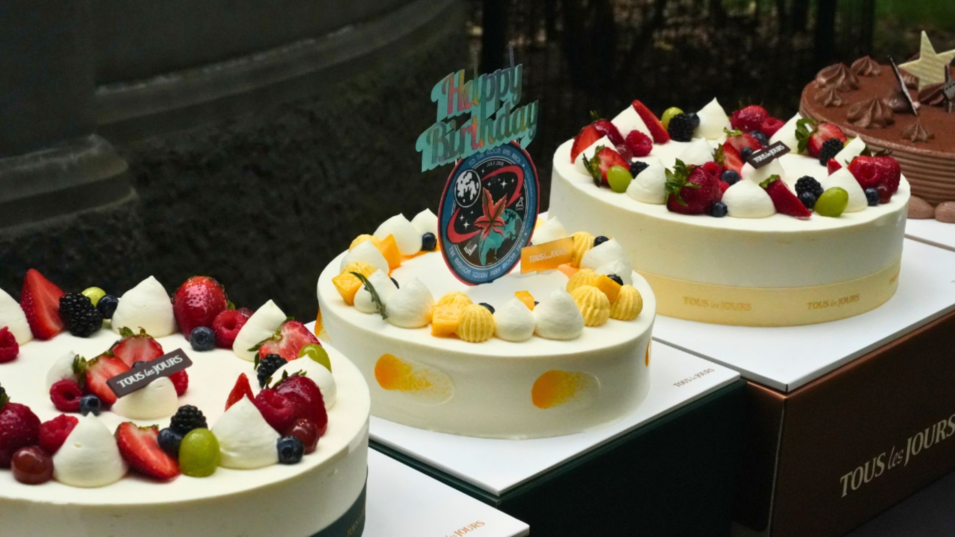 Three cakes, the middle of which has a Happy Birthday moon tree sign.