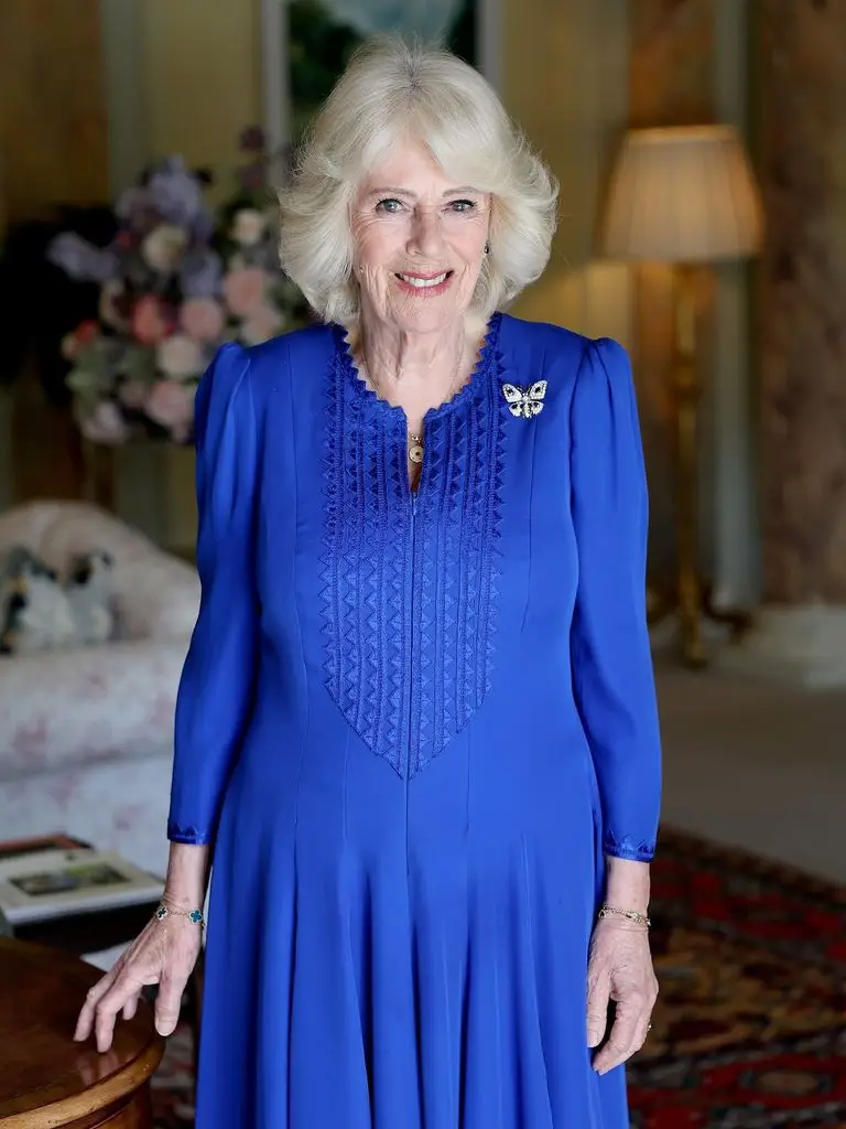 Queen Camilla posing for a 79th birthday portrait in a blue dress