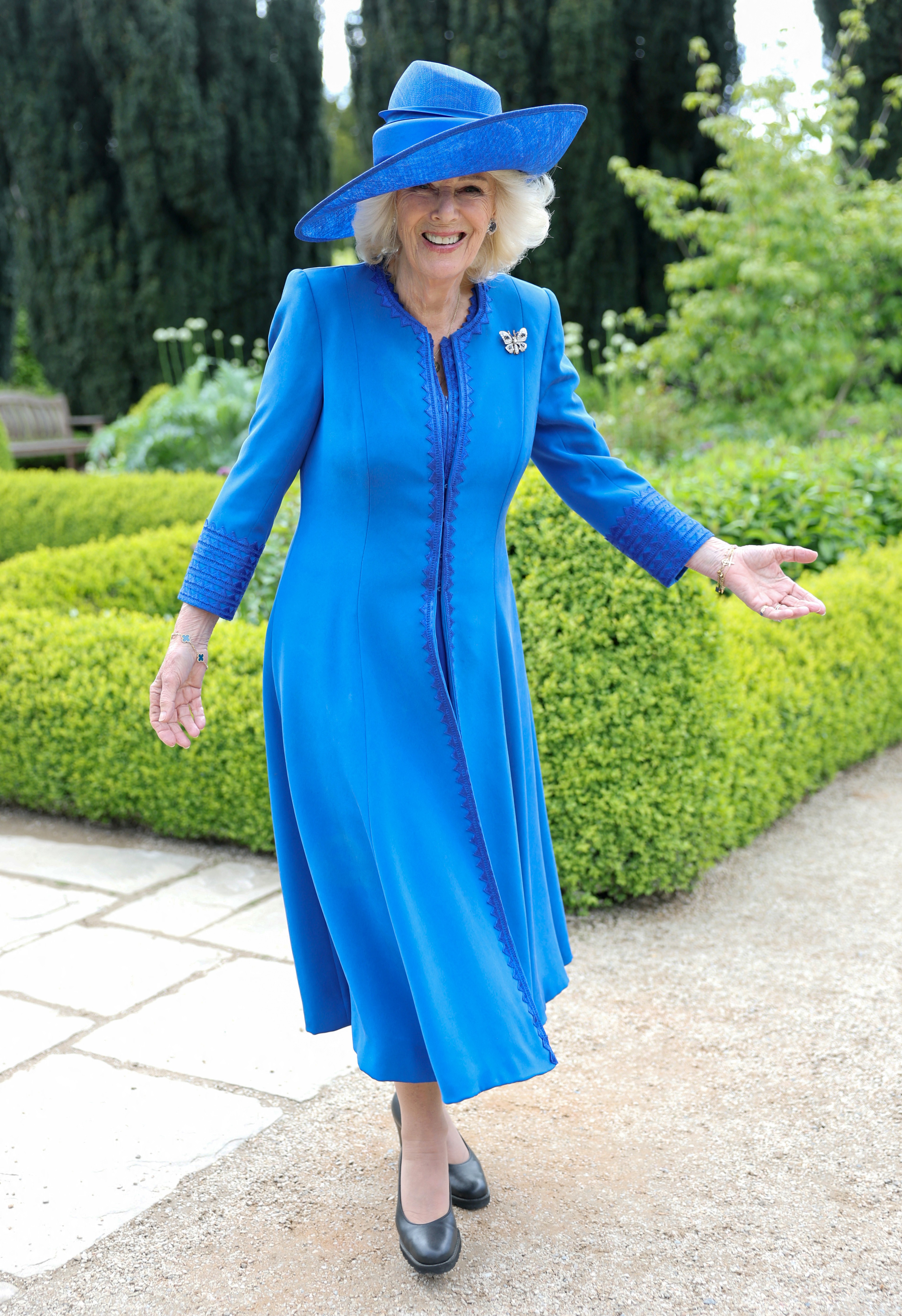 Queen Camilla wearing a blue dress and laughing in the garden at Hillsborough Castle
