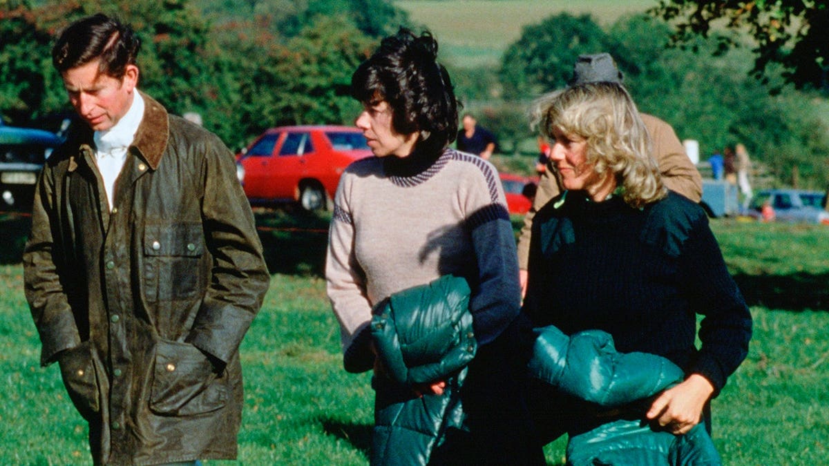 Prince Charles and Camilla Parker-Bowles walk with Lady Sarah Keswick outdoors.