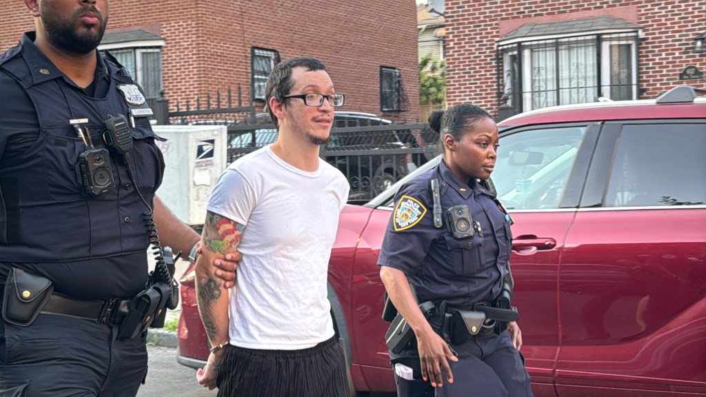 Man in handcuffs being led away by two police officers.