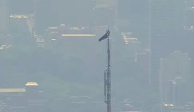 Two people climb Empire State Building antenna with a banner