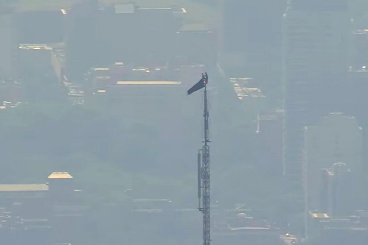 Two people climb Empire State Building antenna with a banner