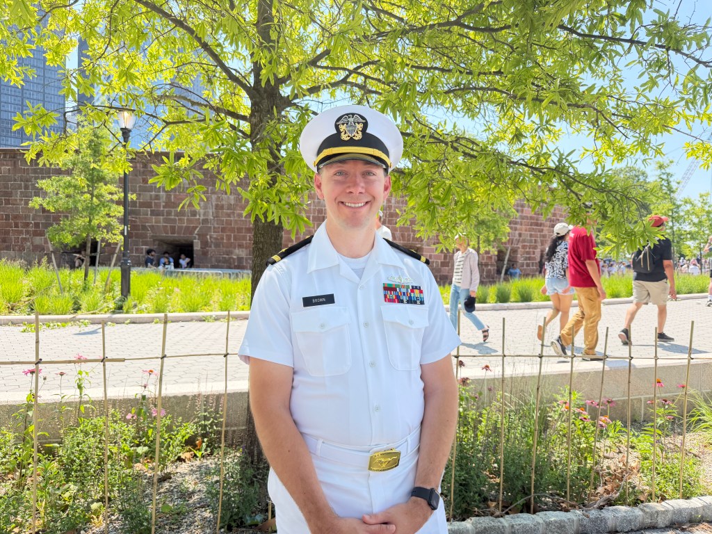 Ben Brown, a Navy reserve officer, smiles at the camera while wearing a white uniform with medals and a gold belt buckle.