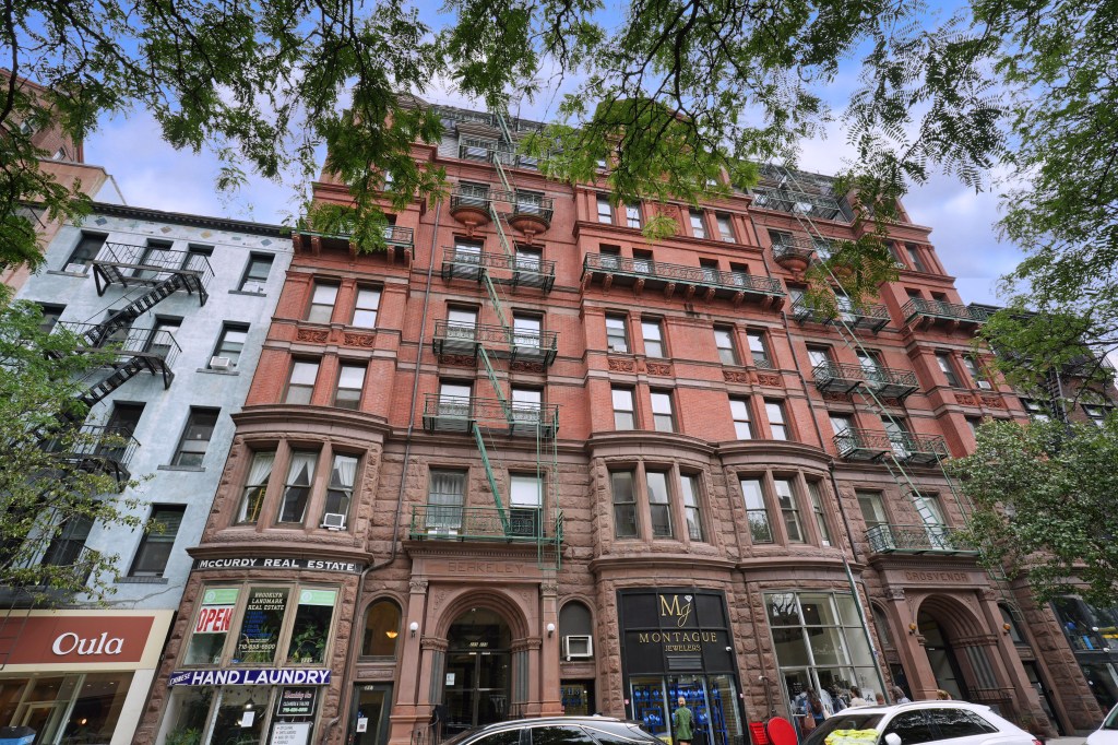 Red Victorian apartment building with stores on the ground floor in Brooklyn.